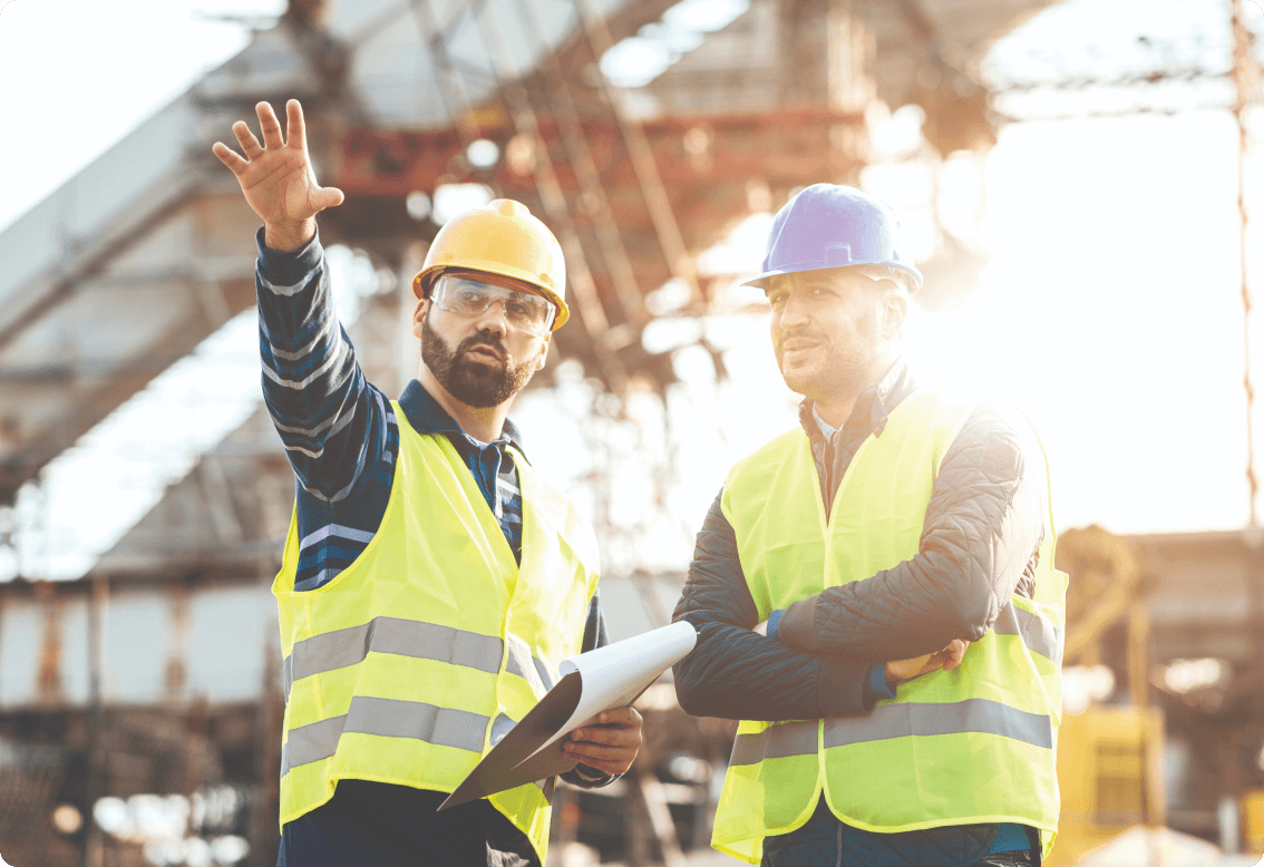 A couple of men talking in reflective vests in a construction site