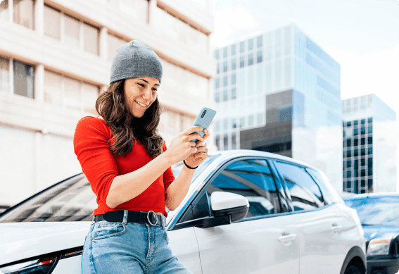 a woman holding a phone and a car