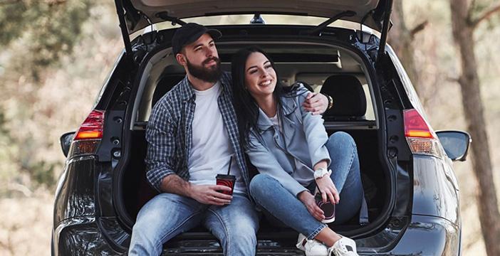 a man and woman sitting in the trunk of a car