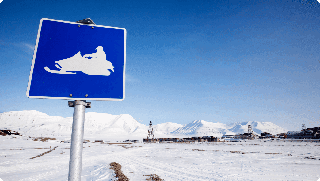 A blue sign with a snowmobile on it for trail paths