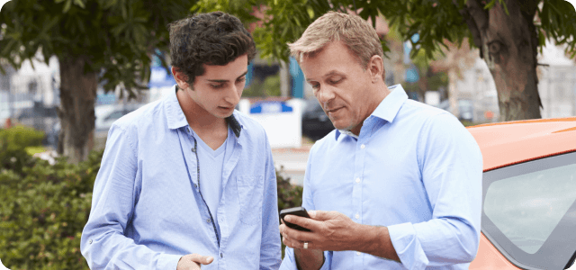 An older man showing a younger man his phone