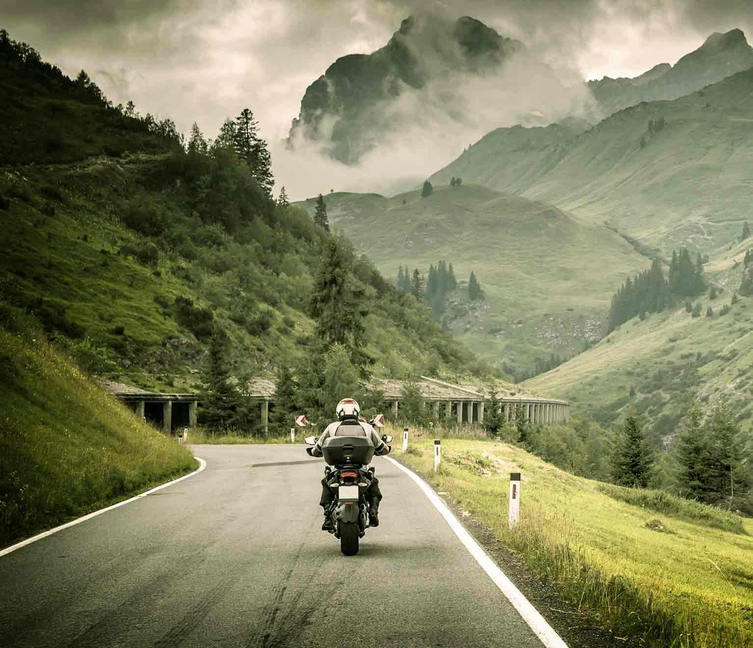 a person riding a motorcycle on a road in the mountains
